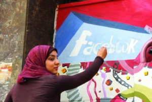 FILE - In this March 30, 2011, file photo. an art student from the University of Helwan paints the Facebook logo on a mural commemorating the revolution that overthrew Hosni Mubarak in the Zamalek neighborhood of Cairo, Egypt. In a statement to The Associated Press on Wednesday, Dec 30, 2015, Facebook said it is “disappointed” that a program providing free basic Internet services to over three million Egyptians has been shut down. It said the service provided Internet access to more than a million people who were not previously connected. (AP Photo/Manoocher Deghati, File)